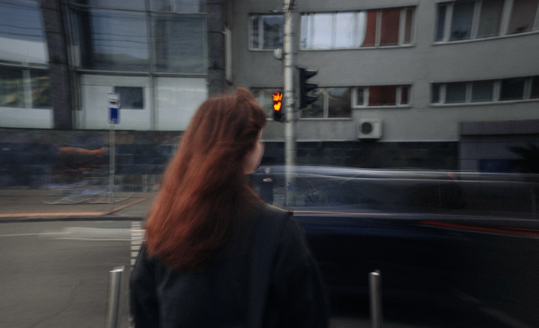 woman in black jacket standing near road during daytime