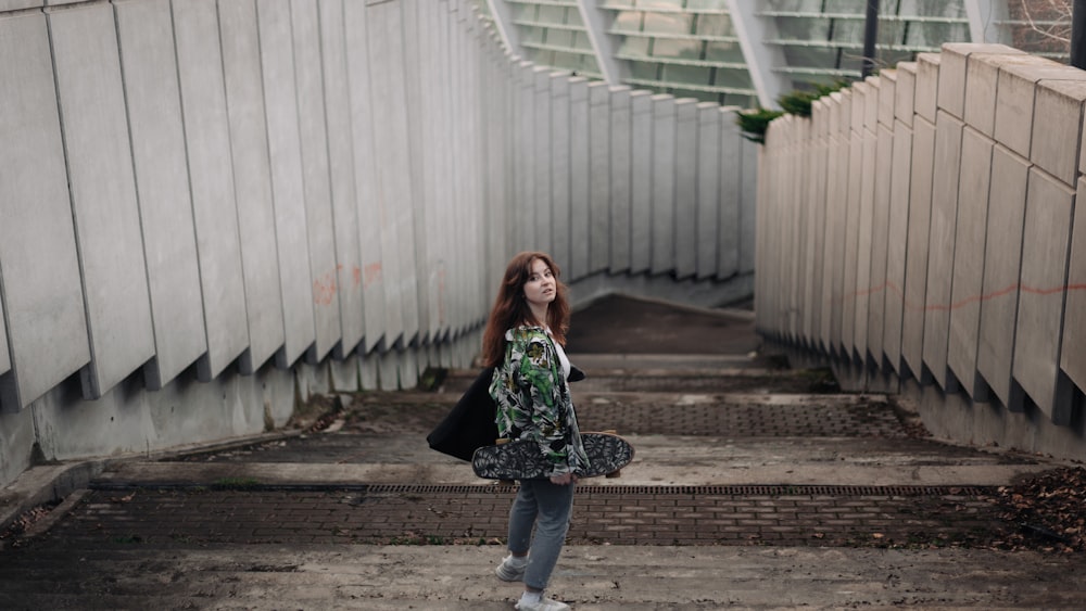 a woman standing in a tunnel holding a skateboard