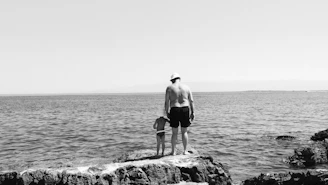 man in black shorts standing on rock near body of water during daytime