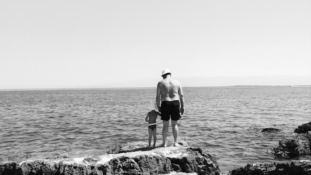 man in black shorts standing on rock near body of water during daytime