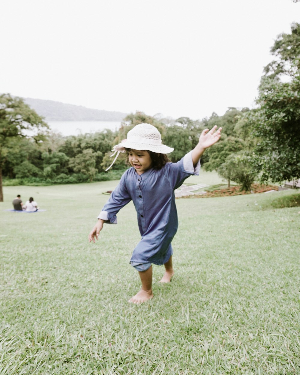 boy in blue t-shirt and blue shorts walking on green grass field during daytime