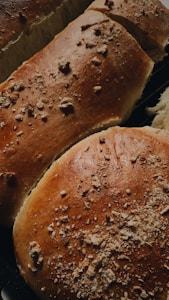 Close-up view of freshly baked bread with a golden brown crust. The surface is sprinkled with crumbs, giving a textured appearance. The bread looks soft and fluffy, indicating it is freshly made.