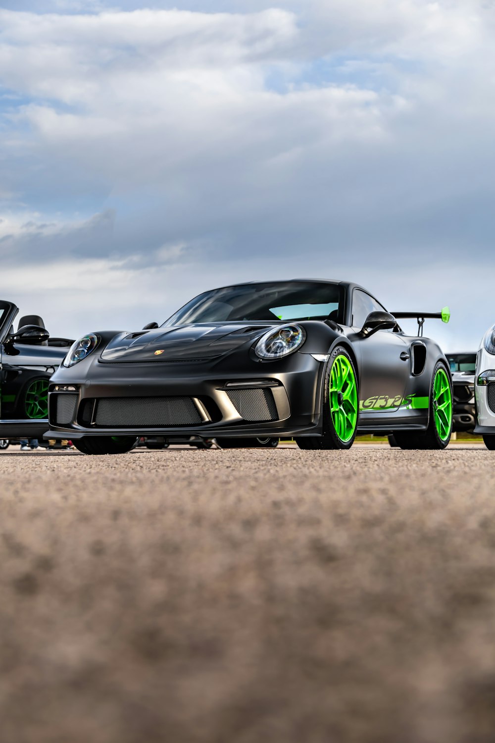 black and green porsche 911 on brown dirt road under gray clouds