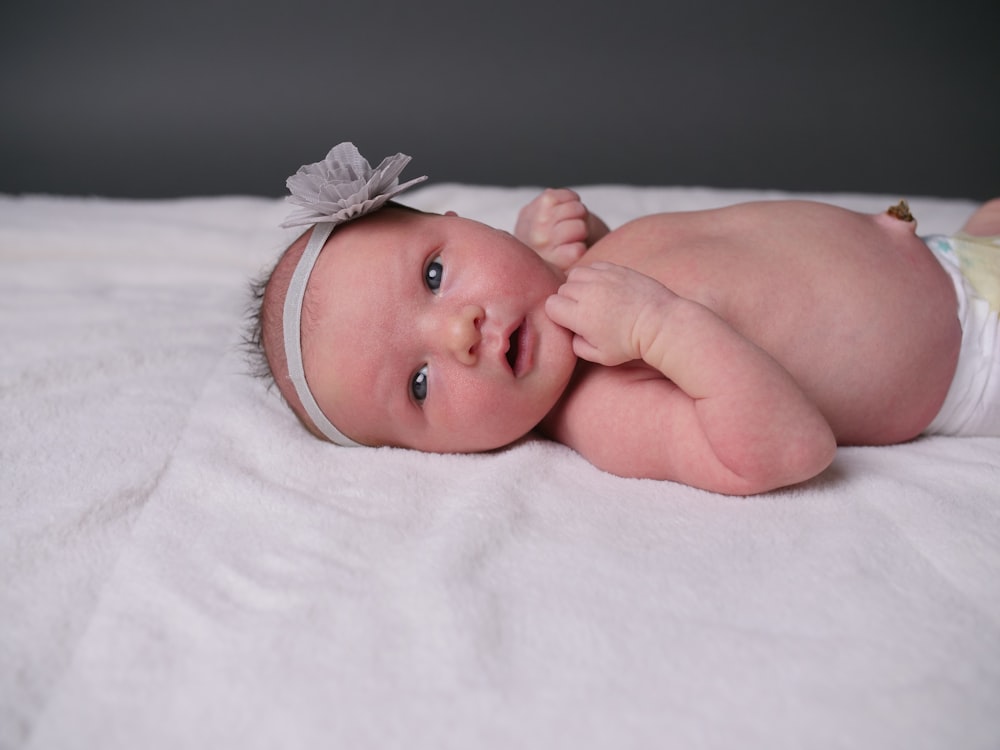 baby lying on white textile