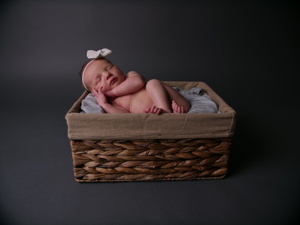 baby lying on brown wicker basket