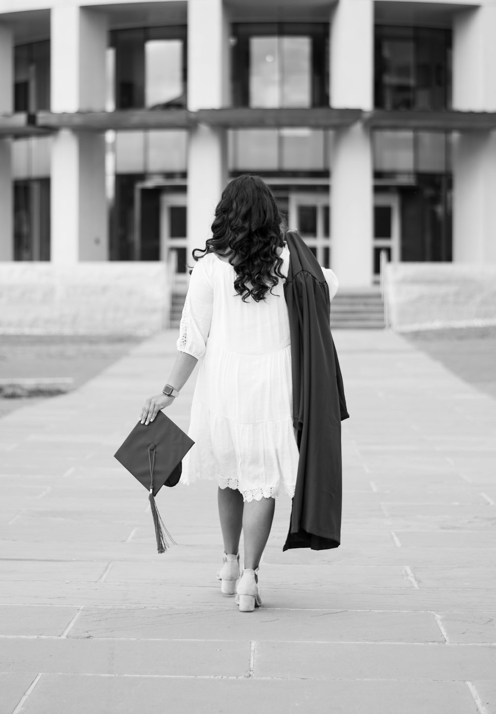 woman in white long sleeve shirt and black skirt walking on sidewalk during daytime