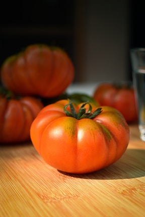 Close-up of juicy heirloom tomatoes ripening on the vine in the sun.