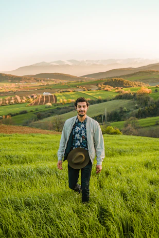 man in blue jacket standing on green grass field during daytime