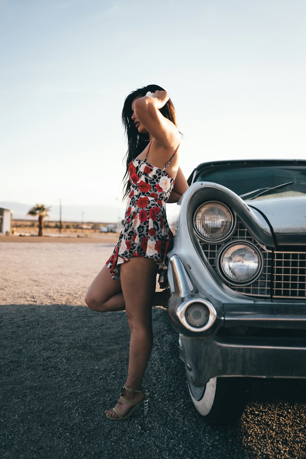 woman in black red and white floral dress leaning on black car