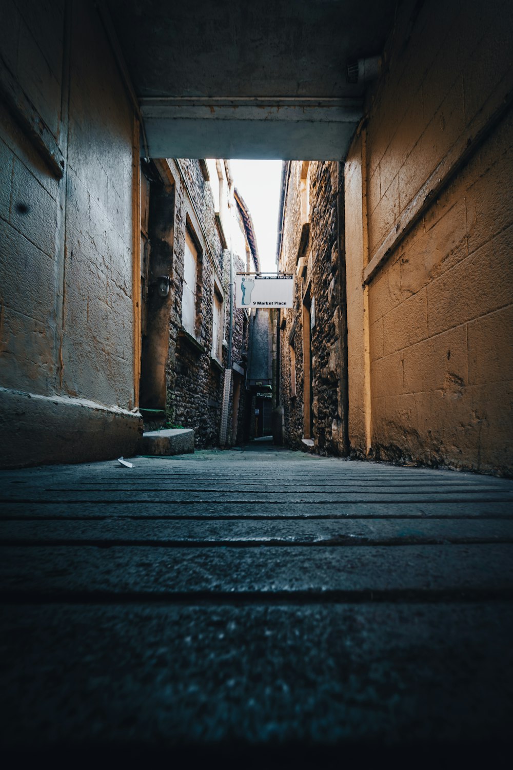 brown wooden pathway between brown brick wall