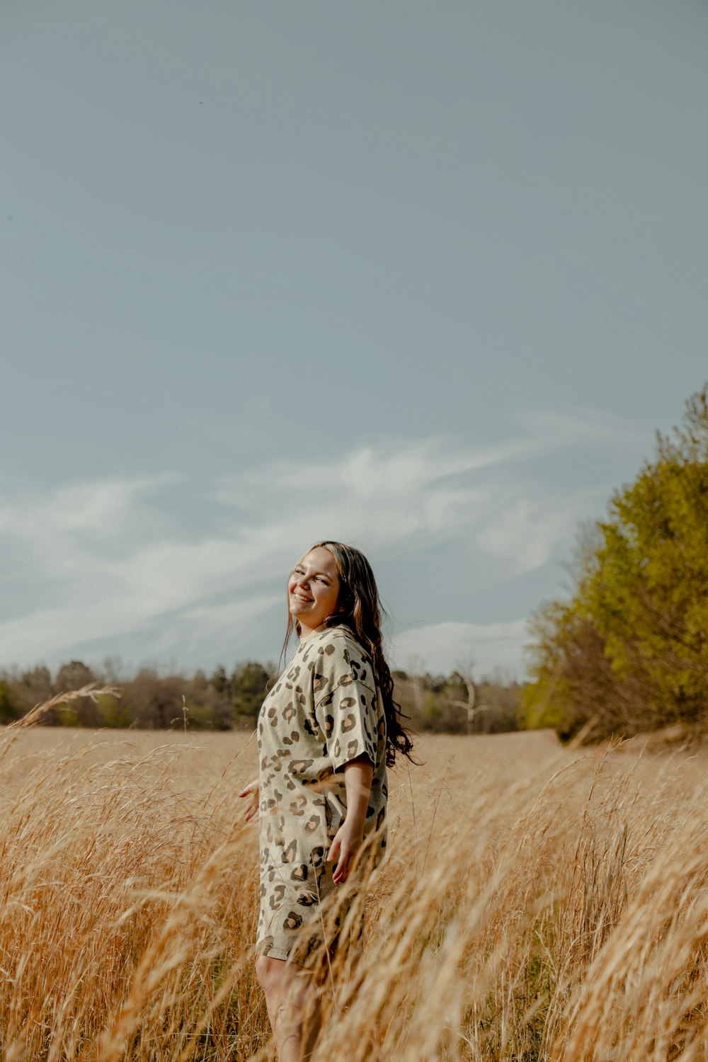 woman in white and black floral dress standing on brown grass field during daytime