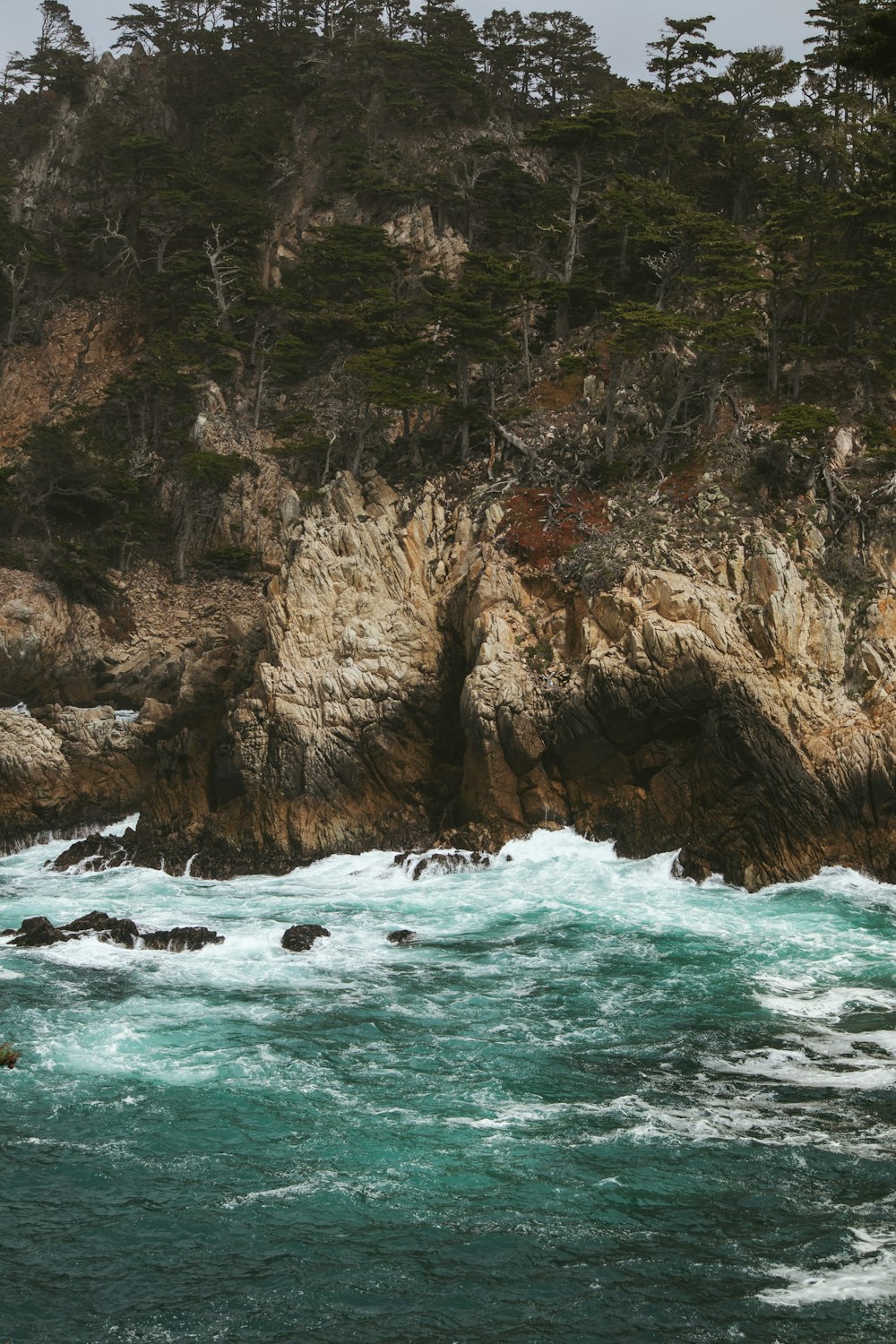 brown rock formation beside body of water during daytime