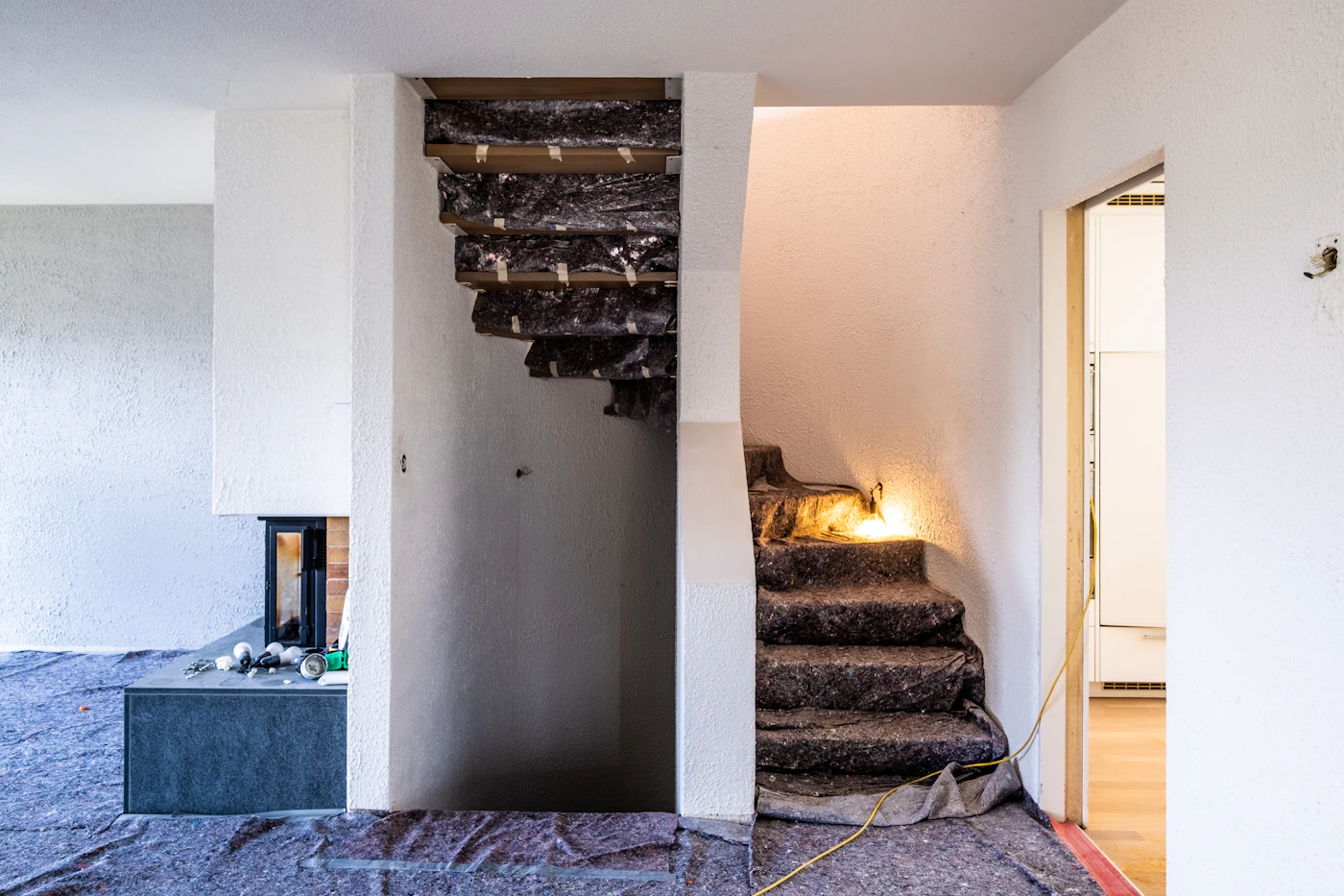 Antes: escalera en obra cubierta con protectores y paredes sin pintar