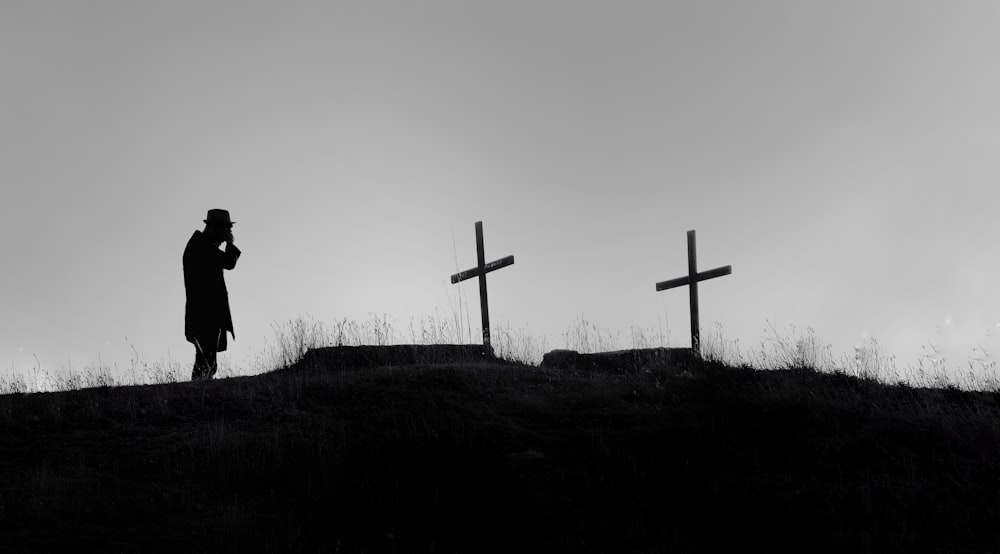 silhueta da pessoa em pé perto da cruz