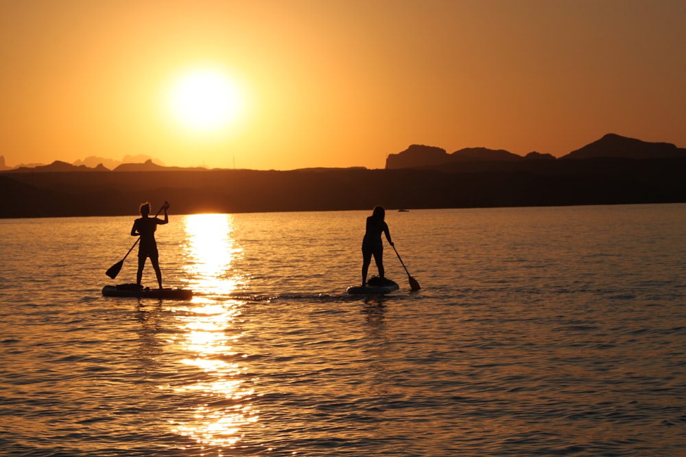 Silhouette von 2 Personen, die während des Sonnenuntergangs am Meeresufer stehen