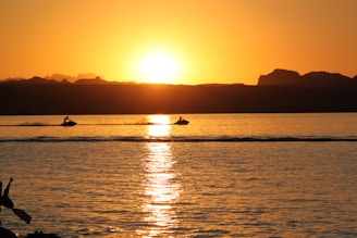 silhouette of person riding on boat during sunset
