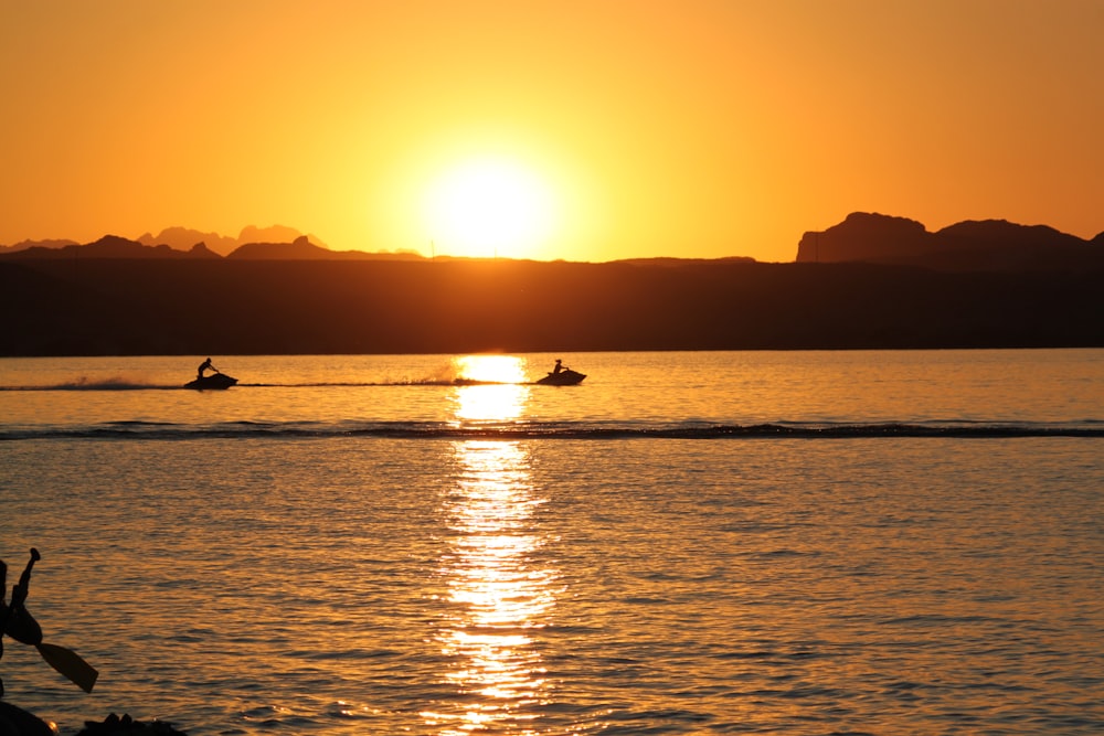 Silueta de la persona que monta en el barco durante la puesta del sol