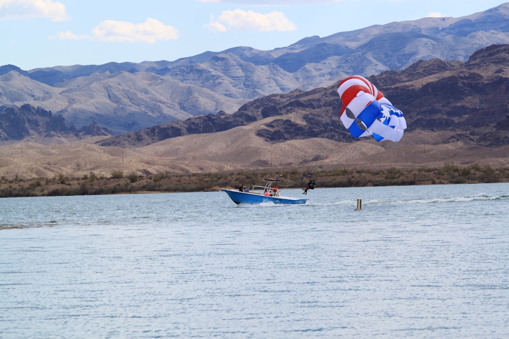 2 people riding on blue and red boat on sea during daytime