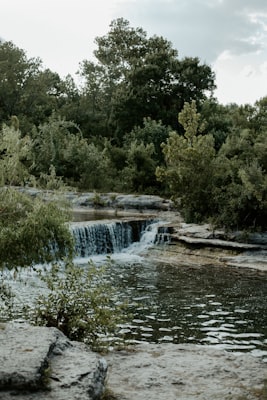 Peaceful waterfall surrounded by green trees at Cook Park in Tigard