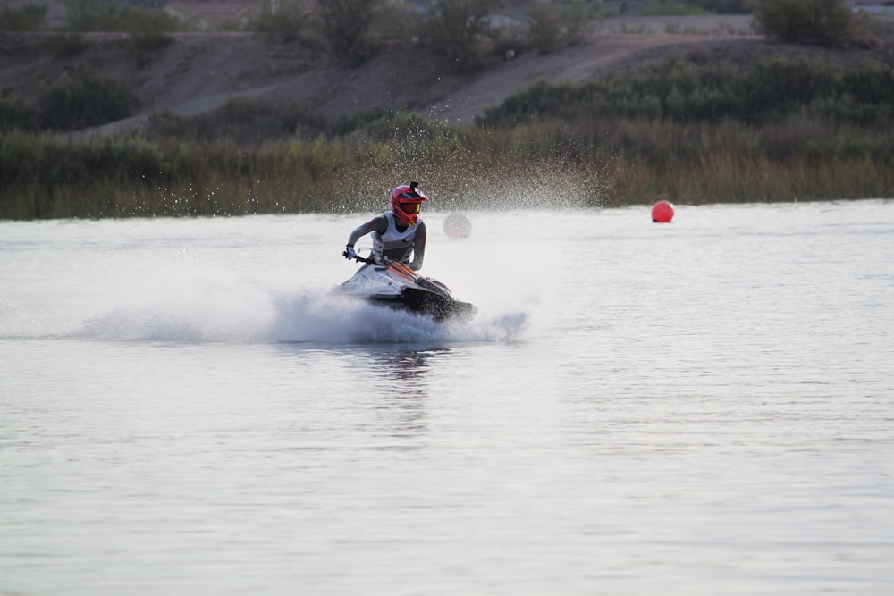 man riding on black and red personal watercraft on body of water during daytime