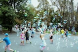 Children playing joyfully in a green park surrounded by modern townhouses and blooming trees.