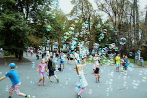 Children playing joyfully in a green park surrounded by modern townhouses and blooming trees.