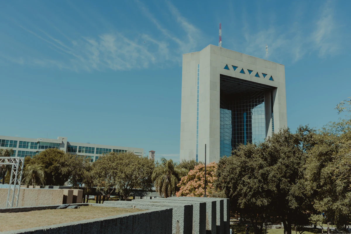 White concrete building near green trees under blue sky during daytime
