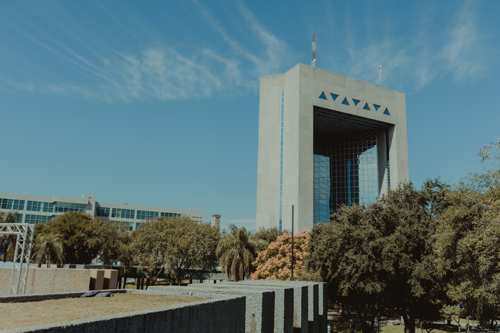 white concrete building near green trees under blue sky during daytime