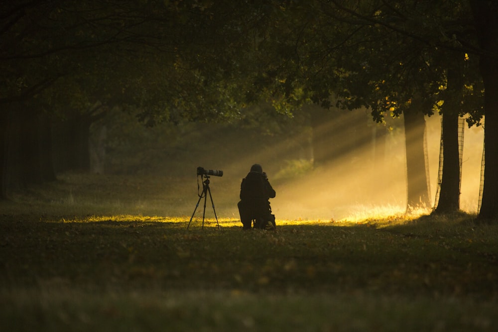 man in black jacket standing on green grass field near trees during daytime