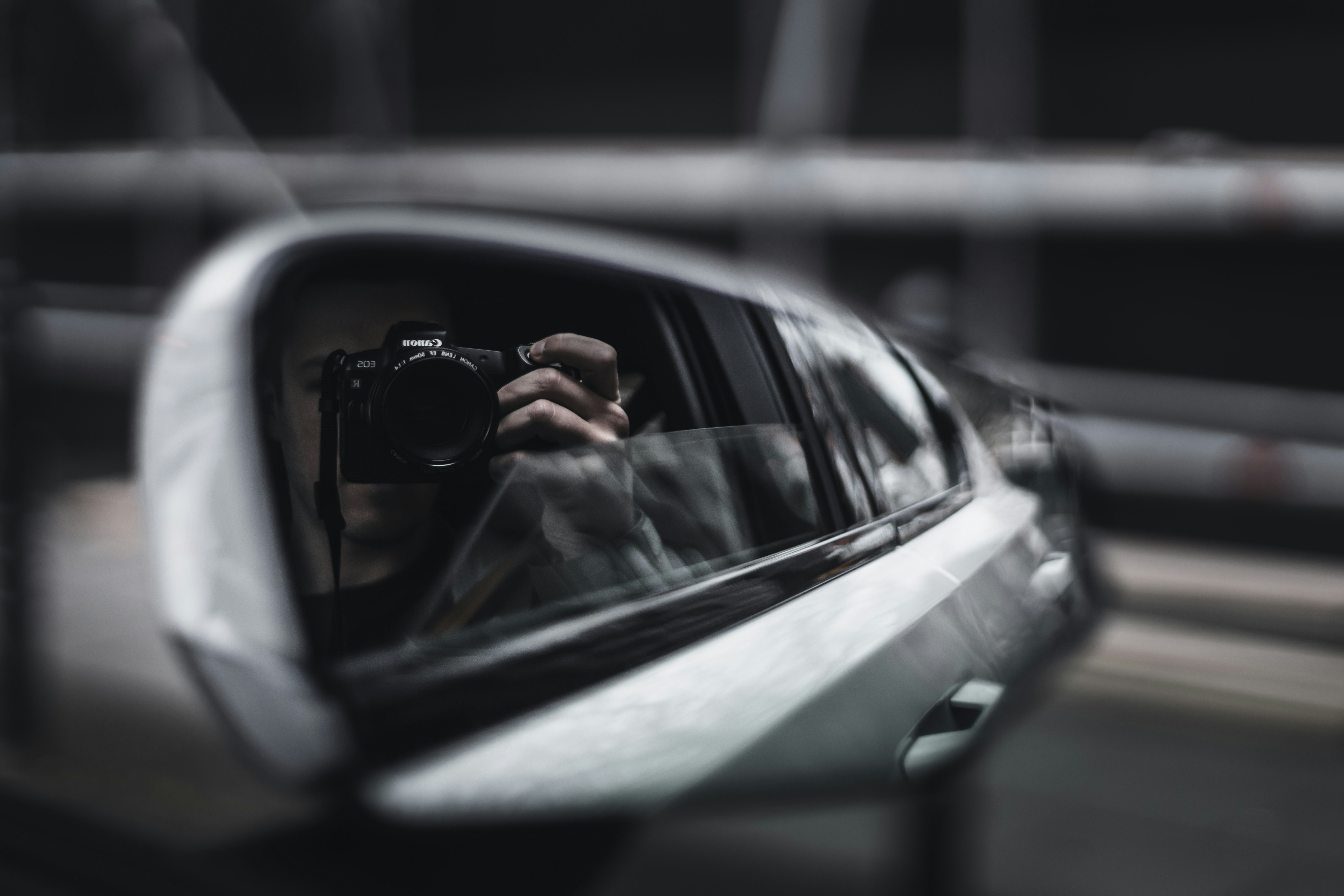 person taking photo of car side mirror