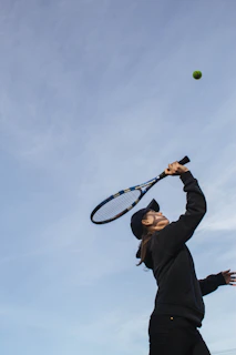 A relaxed tennis player swinging a racket with a soft, flowing motion on a sunny court.