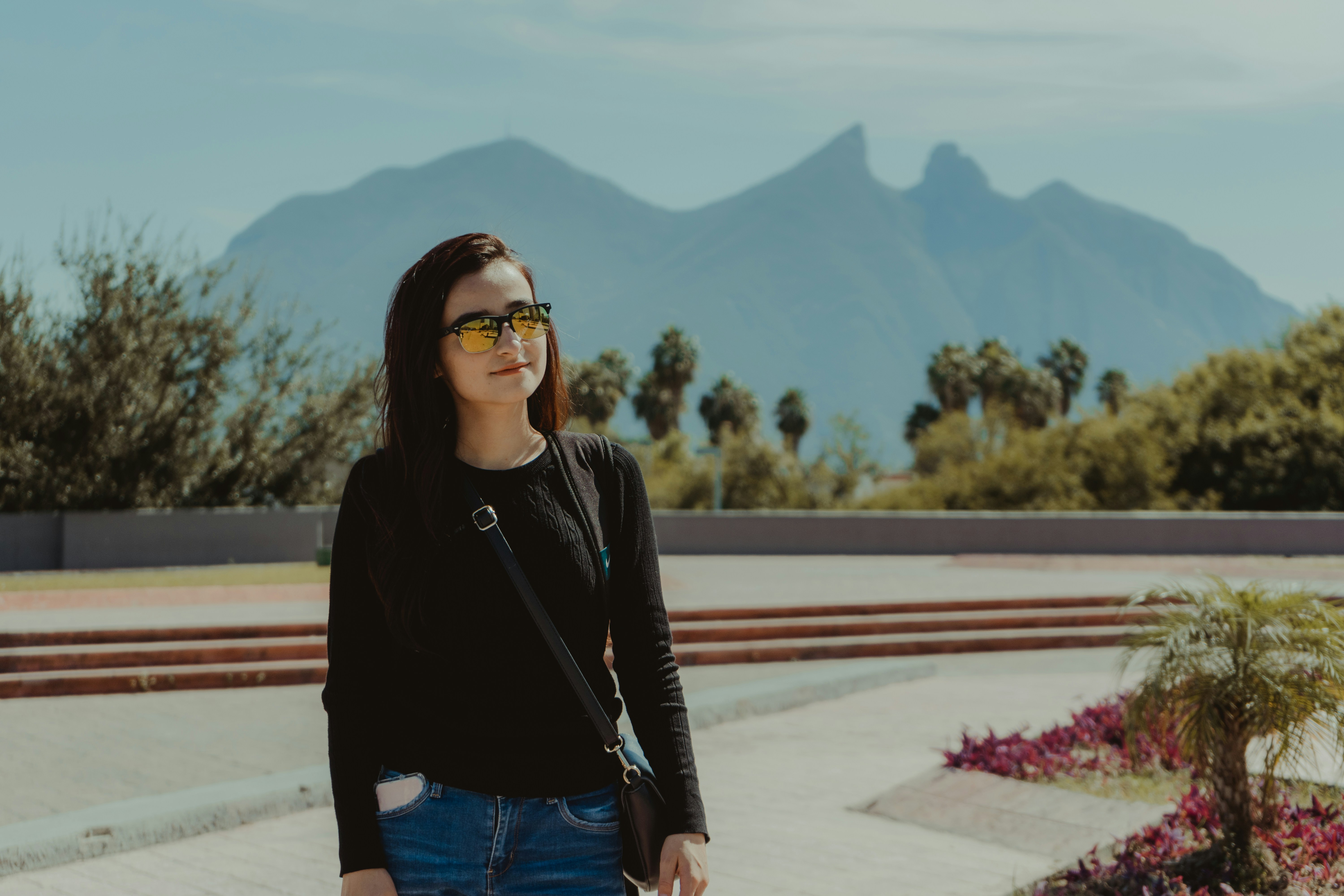 woman in black jacket and blue denim jeans standing on road during daytime