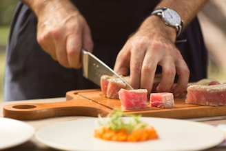 person slicing raw meat on chopping board
