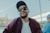 man in white crew neck shirt and purple jacket wearing black sunglasses