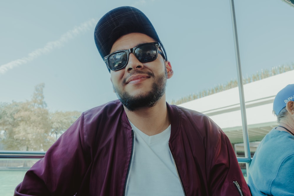 man in white crew neck shirt and purple jacket wearing black sunglasses