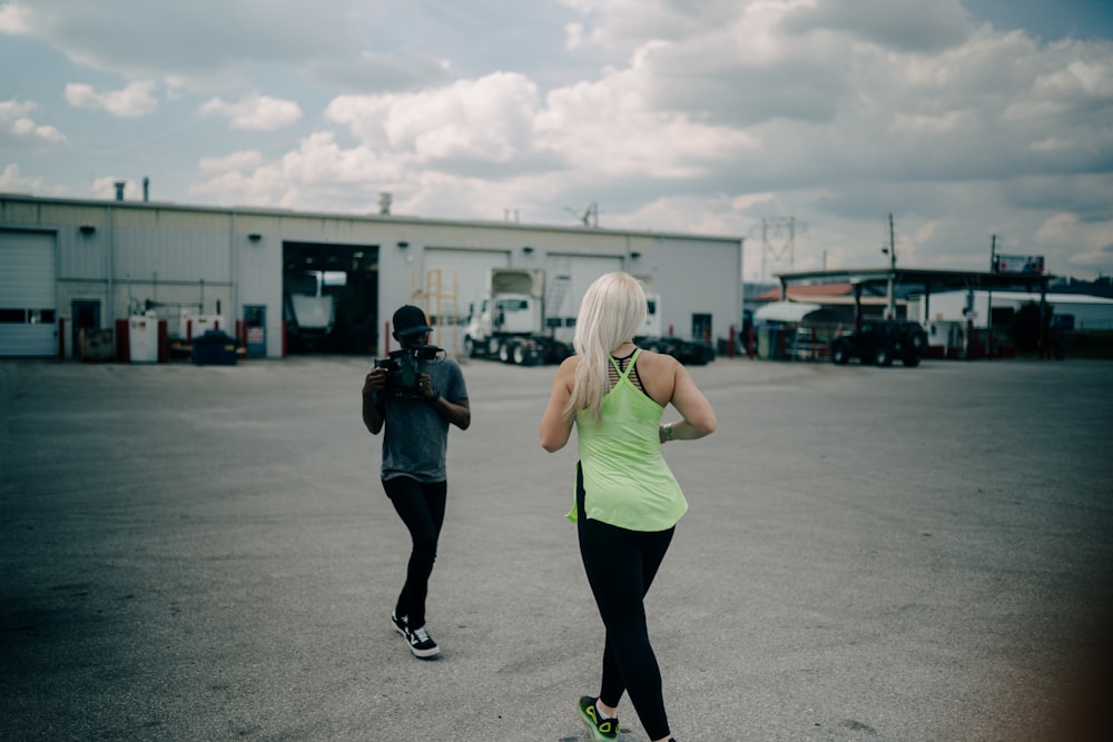 woman in green tank top and black leggings standing on road during daytime