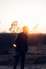 A filmmaker behind the camera capturing a serene outdoor scene at sunset.