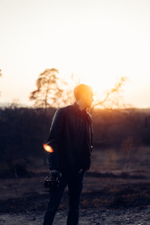 A photographer holding a prized camera, capturing the golden hour outdoors.