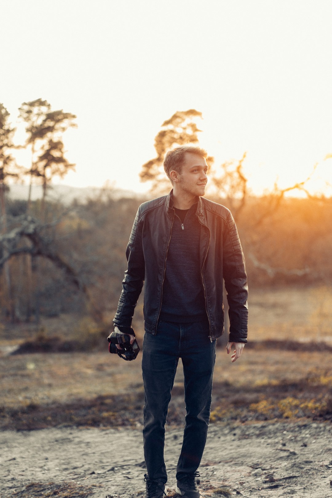 man in black leather jacket standing on grass field during daytime
