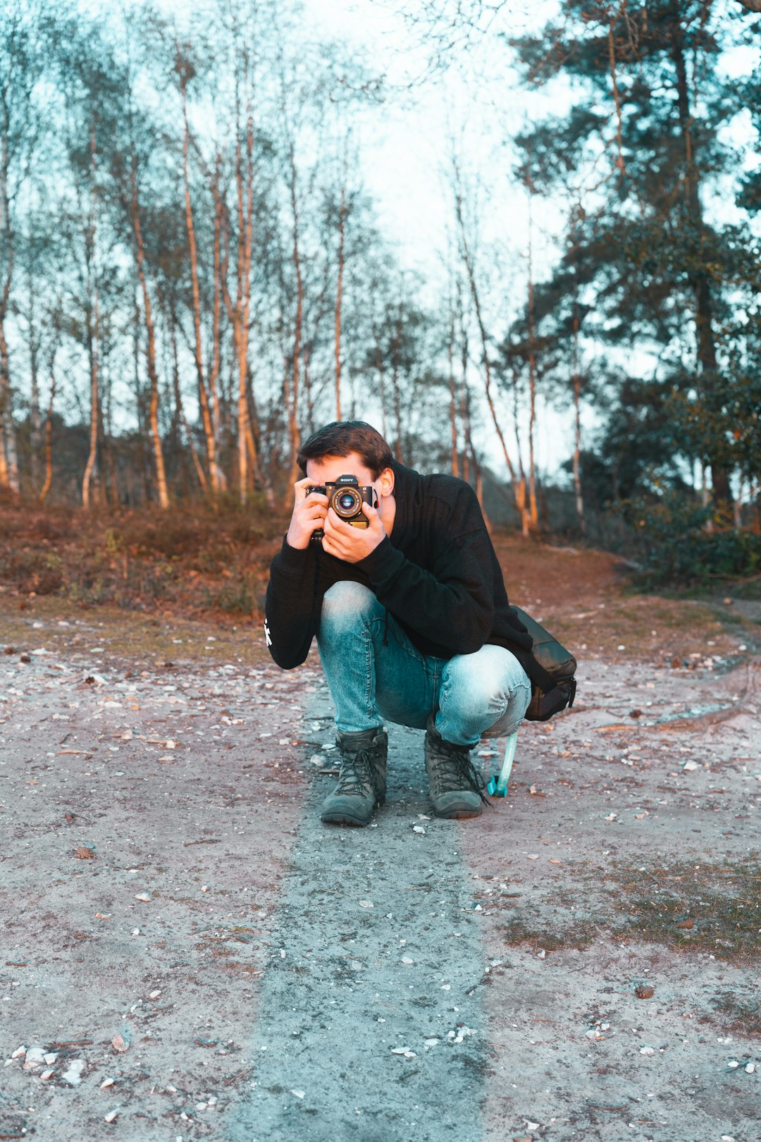 woman in black jacket and blue denim jeans sitting on ground