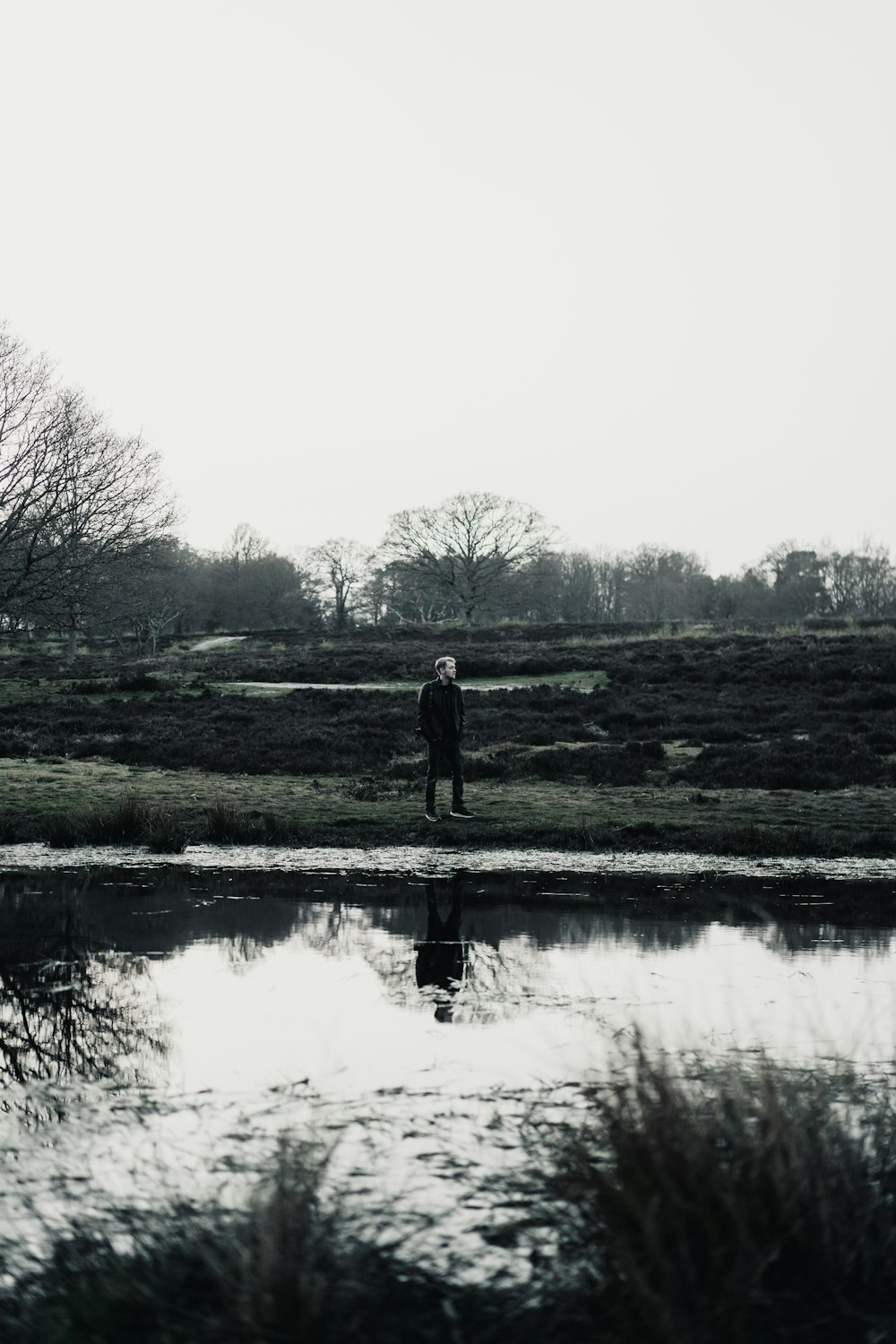 낮에 호수 근처의 푸른 잔디밭에 서 있는 남자