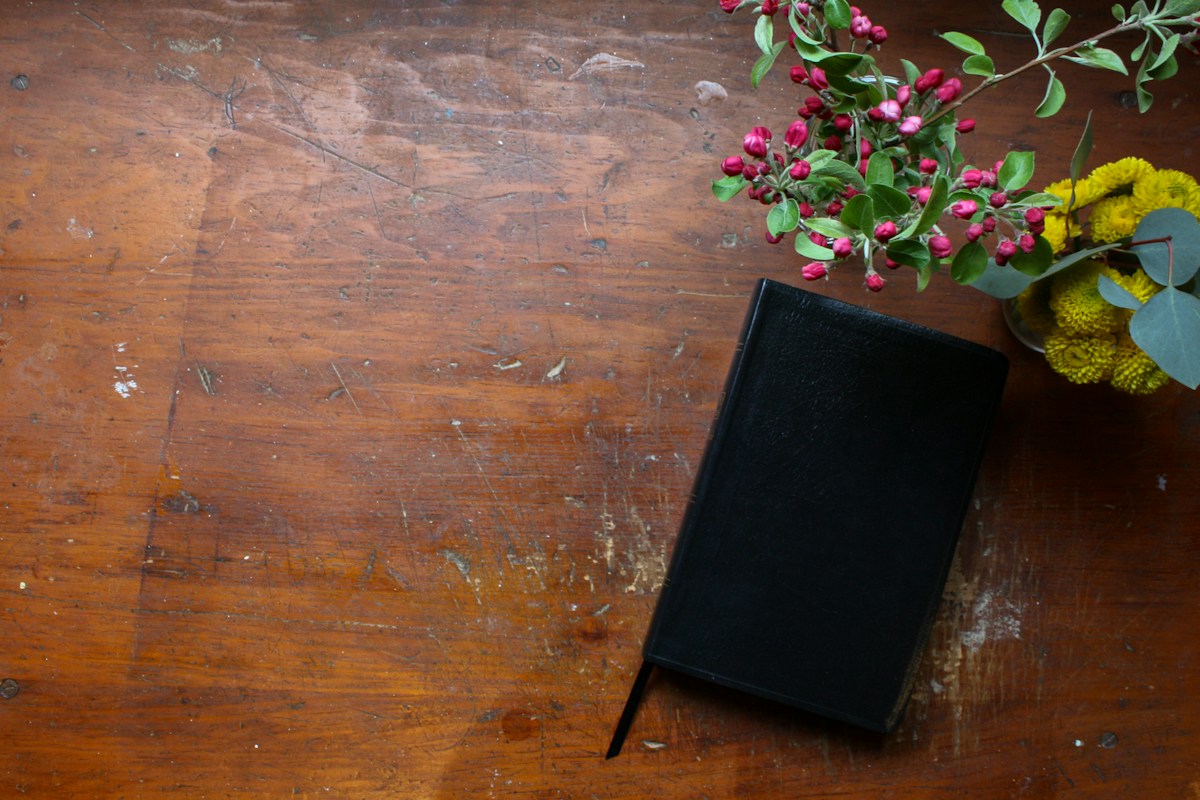 Black book on a brown wooden table, suitable for graduation party planning inspiration.