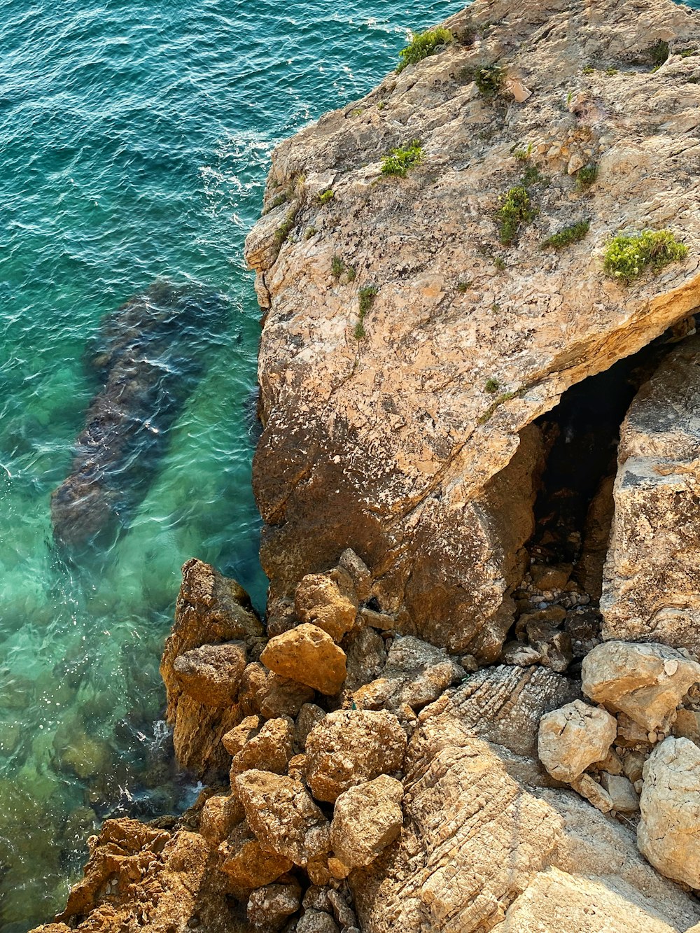 Formación rocosa marrón junto al cuerpo de agua durante el día