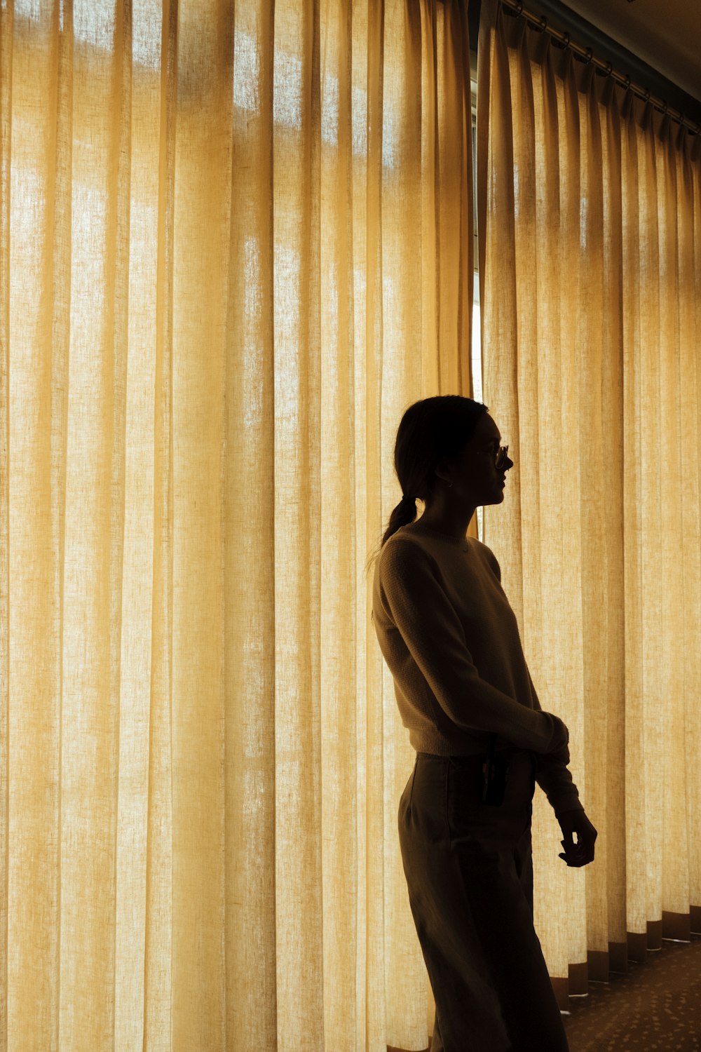 silhouette of woman standing in front of brown curtain