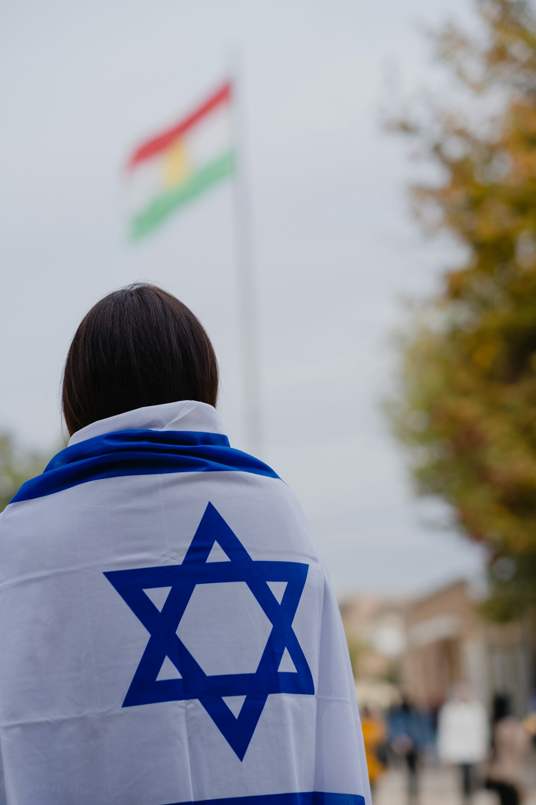 woman in white and blue hoodie standing near green trees during daytime