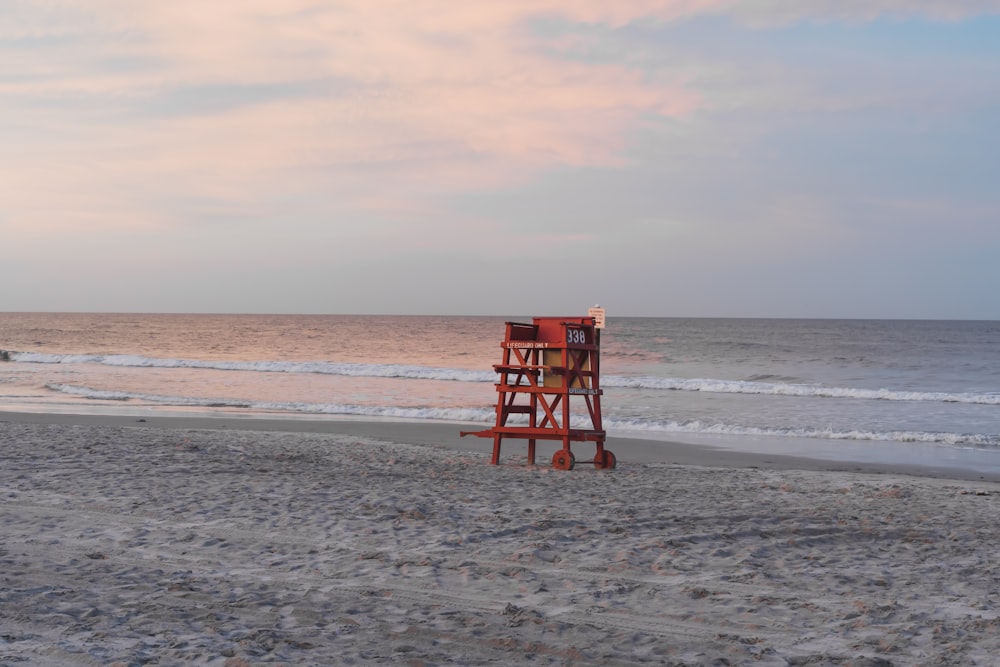 낮 동안 해변에 빨간 나무 인명 구조 의자