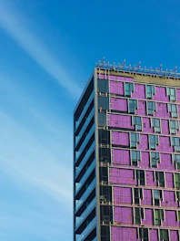 A sleek modular building under construction with neon purple and bronze accents.