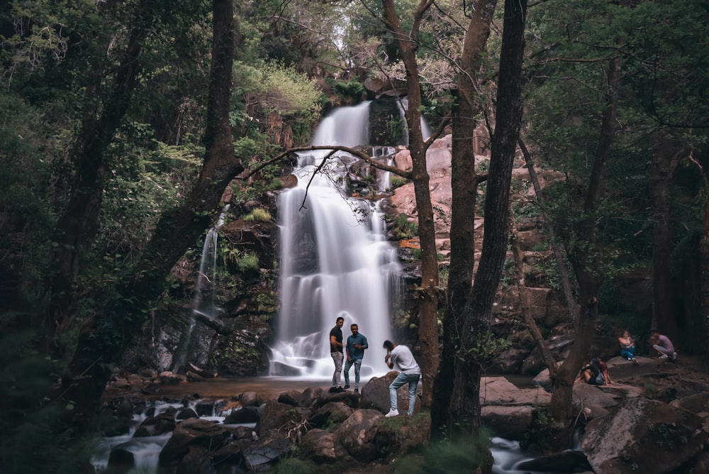 people standing on rock near waterfalls during daytime