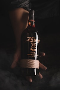 Elegant bottle of rum infused with cannabis leaves resting on a polished wooden bar.