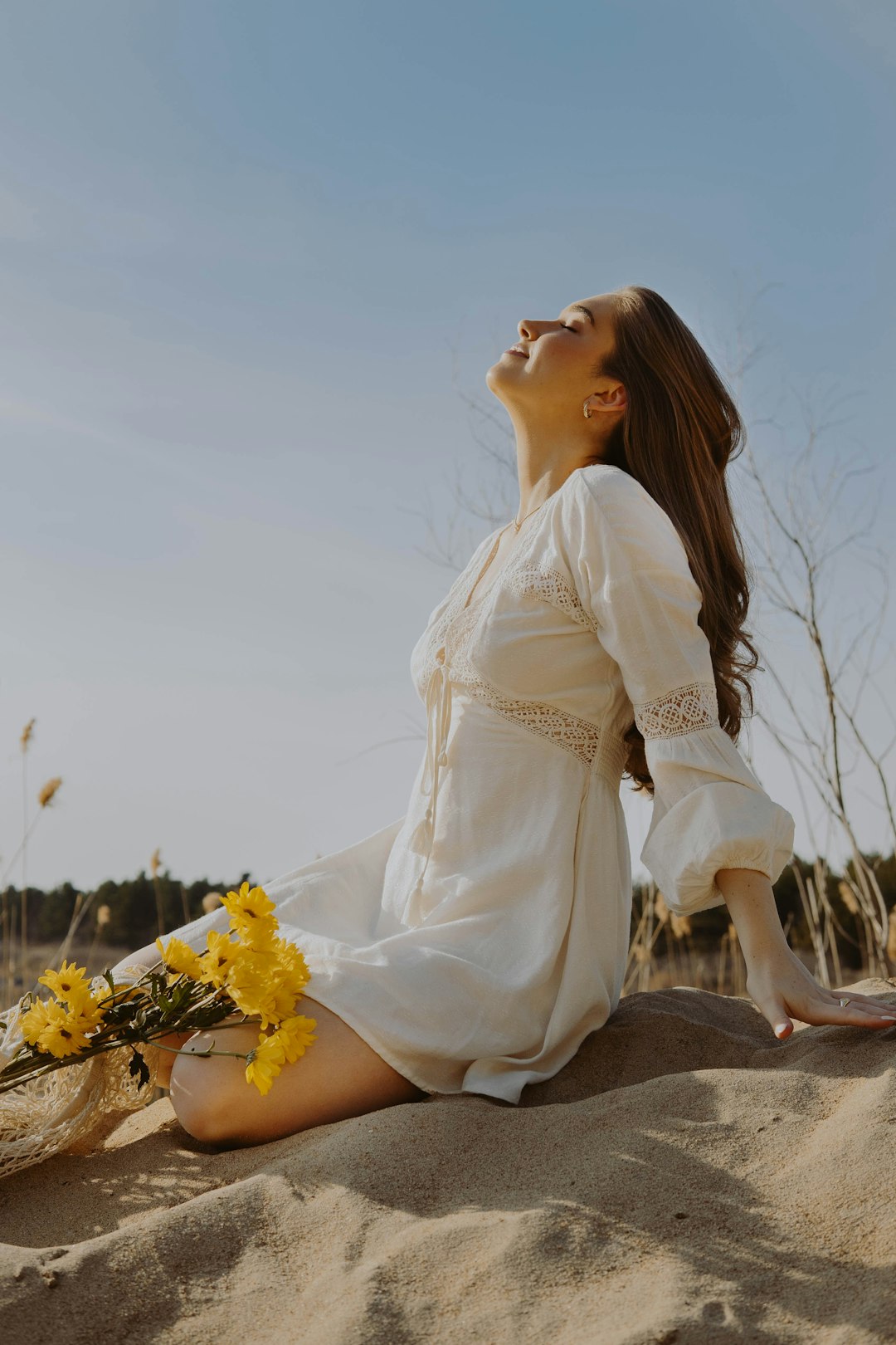 woman in white dress sitting on brown rock during daytime